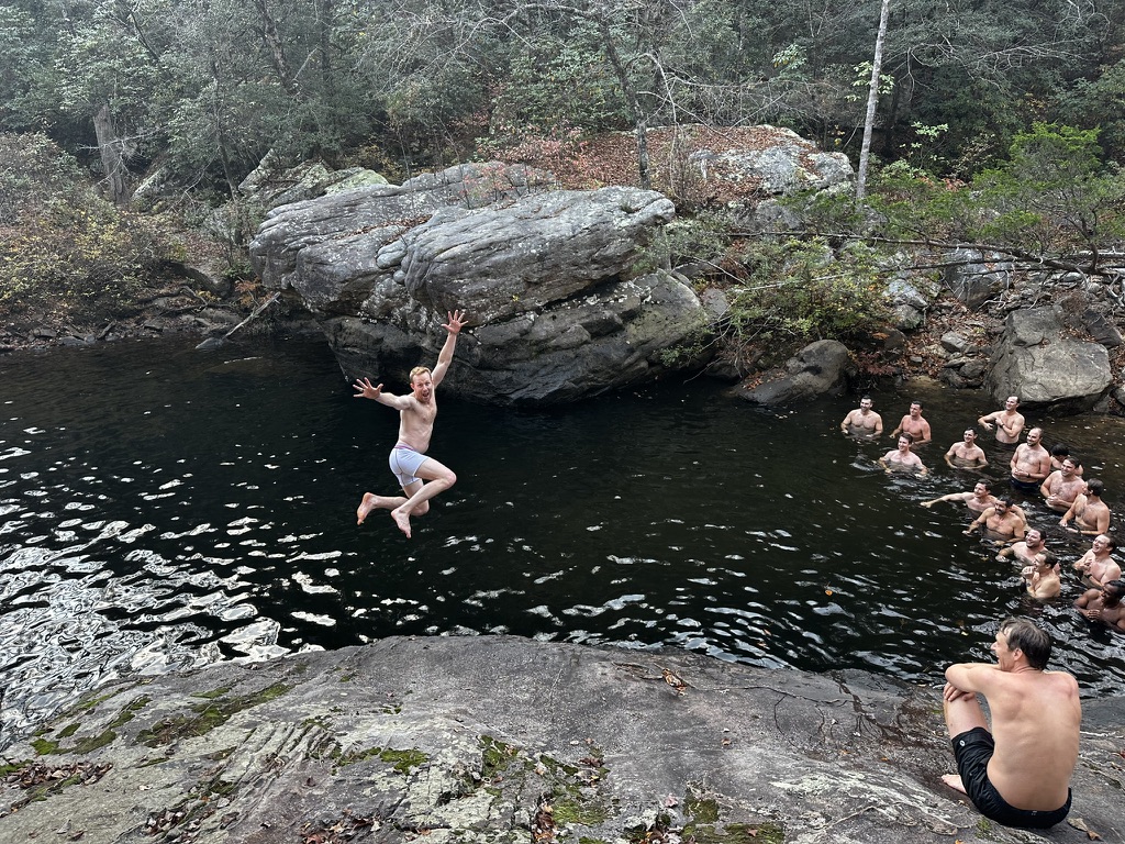 Man jumping off the cliff into water